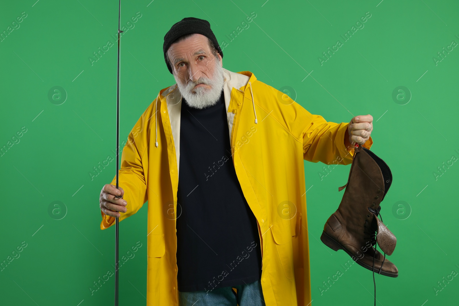 Photo of Fisherman with rod and old boot on green background