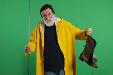 Fisherman with rod and old boot on green background