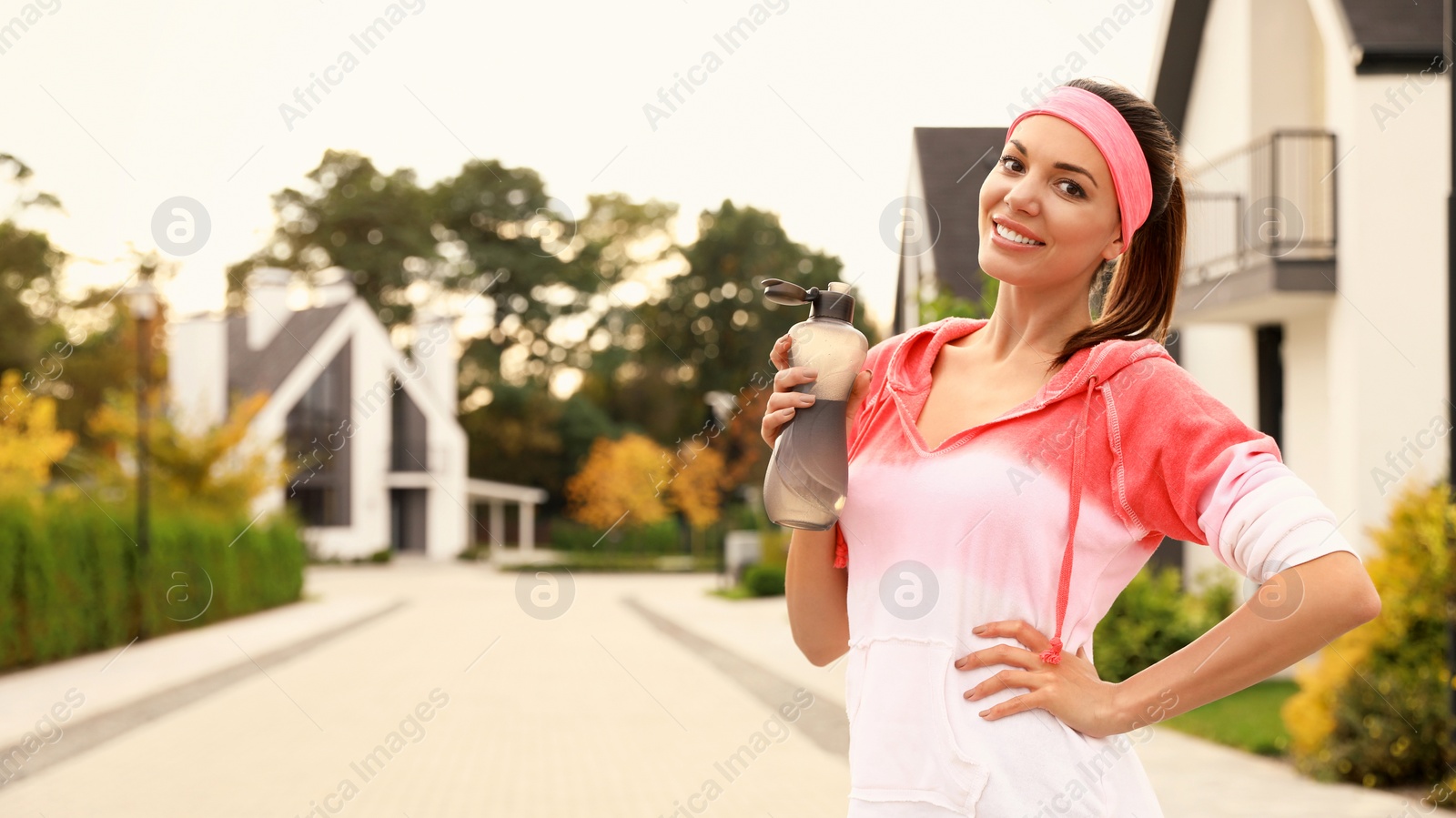 Photo of Beautiful sporty woman drinking water after running on street. Healthy lifestyle