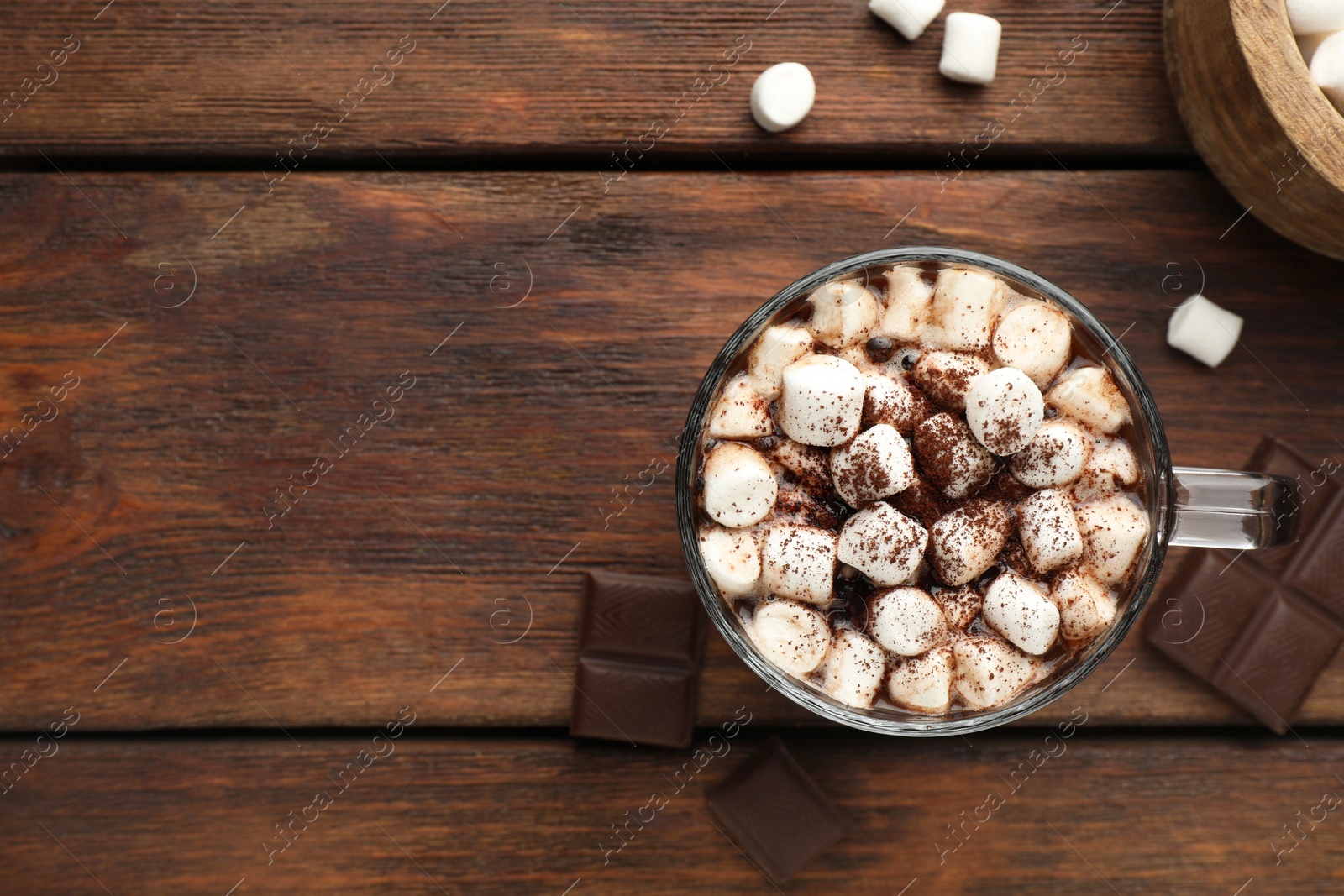 Photo of Cup of aromatic hot chocolate with marshmallows and cocoa powder on wooden table, flat lay. Space for text