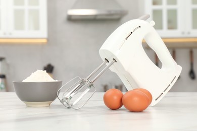 Photo of Modern mixer, eggs and bowl with flour on white marble table in kitchen