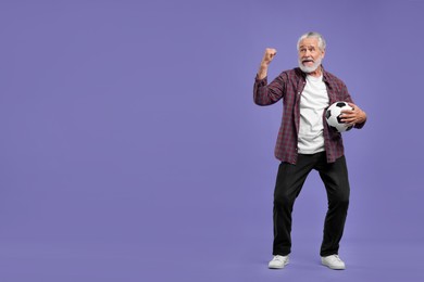 Photo of Senior sports fan with soccer ball on purple background, space for text