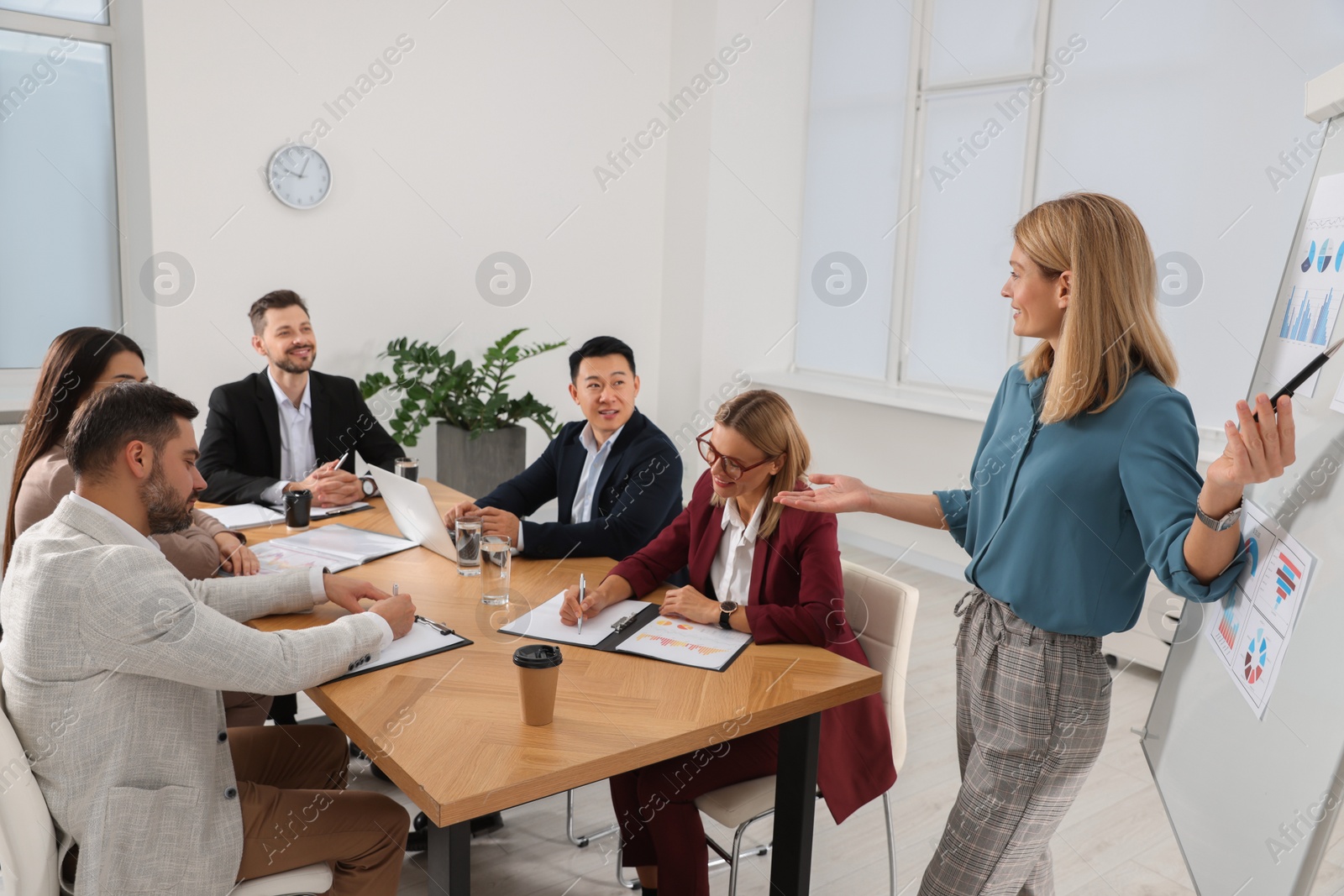 Photo of Businesswoman showing charts near flipchart on meeting in office