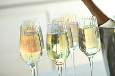Photo of Glasses of champagne and bottle on blurred background, closeup