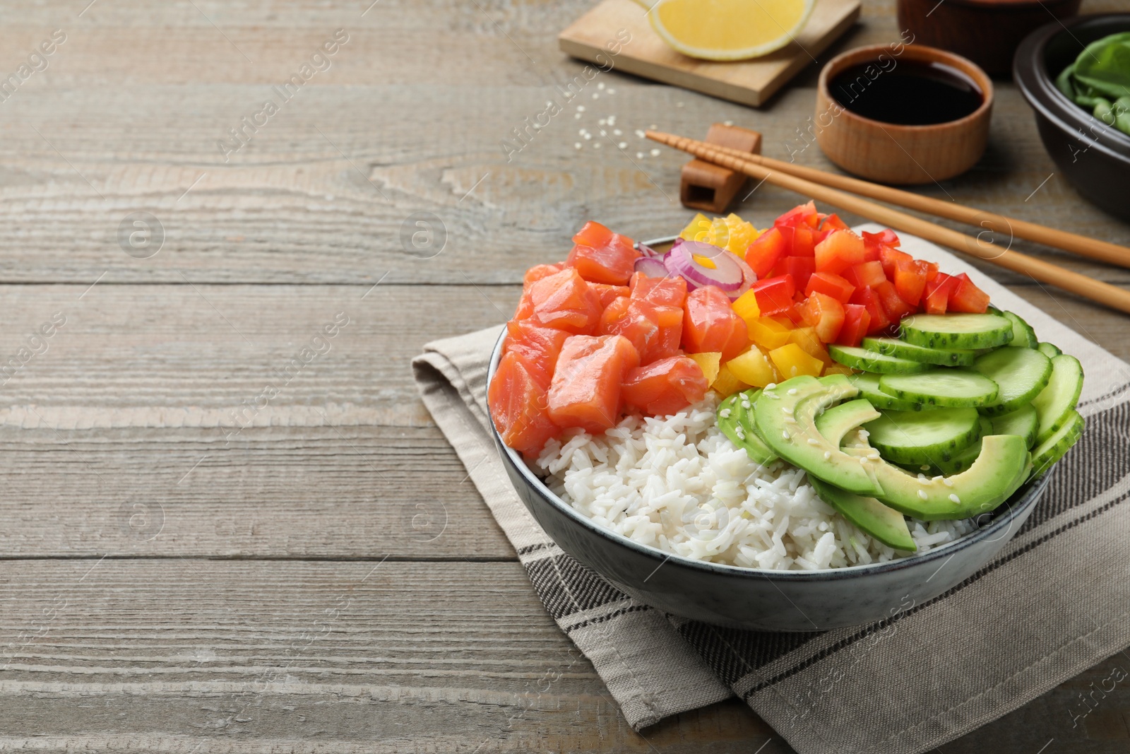 Photo of Delicious poke bowl with salmon and vegetables served on wooden table. Space for text