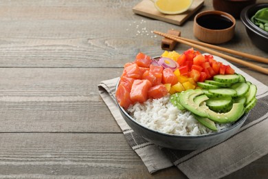 Delicious poke bowl with salmon and vegetables served on wooden table. Space for text