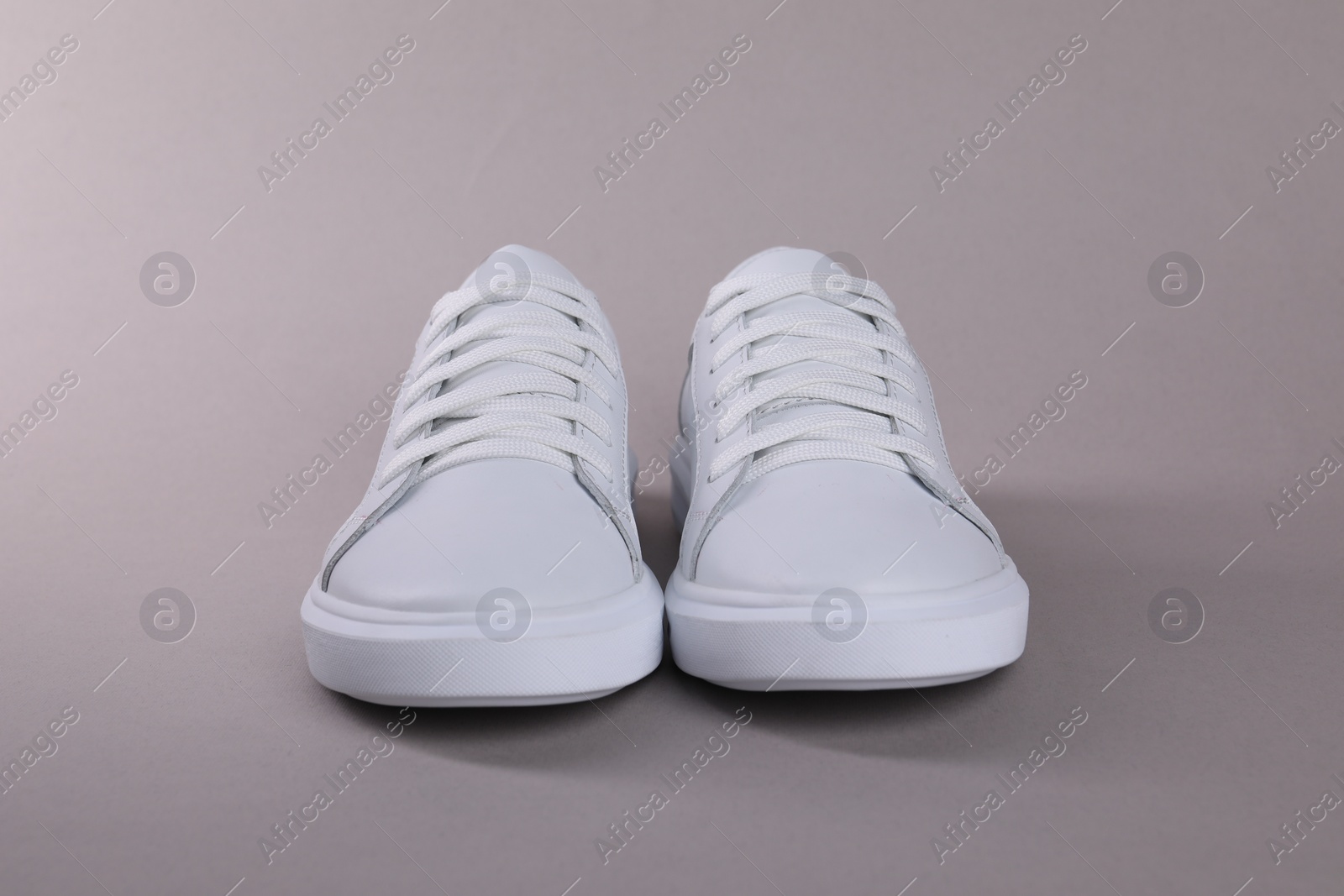 Photo of Pair of stylish white sneakers on grey background