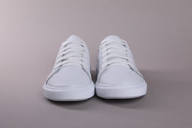 Photo of Pair of stylish white sneakers on grey background