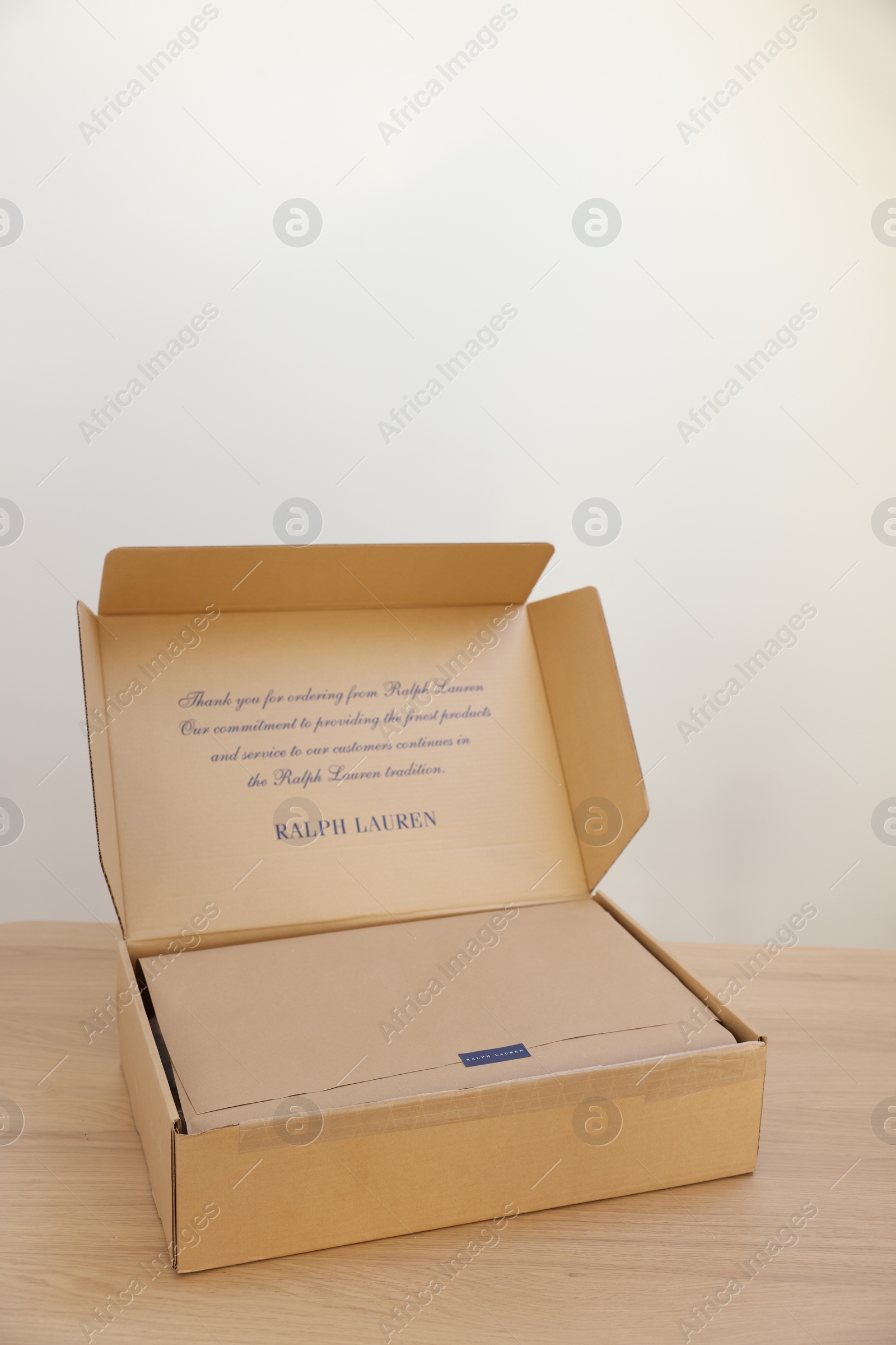 Photo of Leiden, Netherlands - December 6, 2023: Open box with Ralph Lauren garment on wooden table