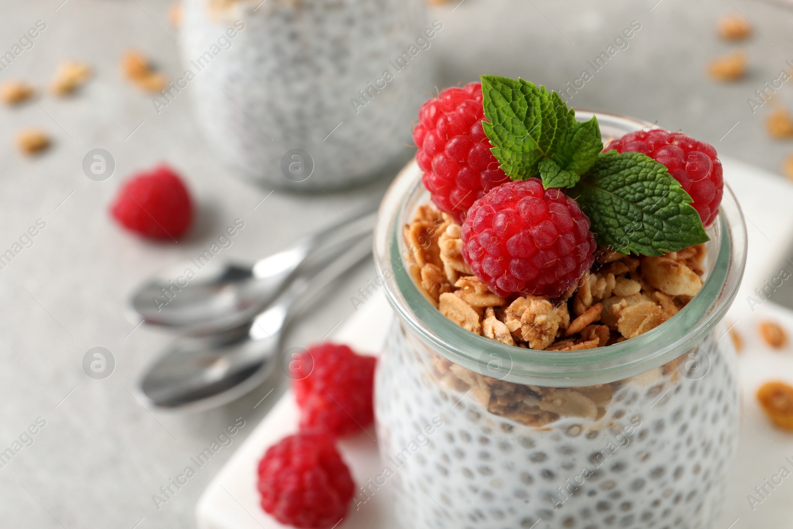 Photo of Delicious chia pudding with raspberries and granola in jar, closeup. Space for text