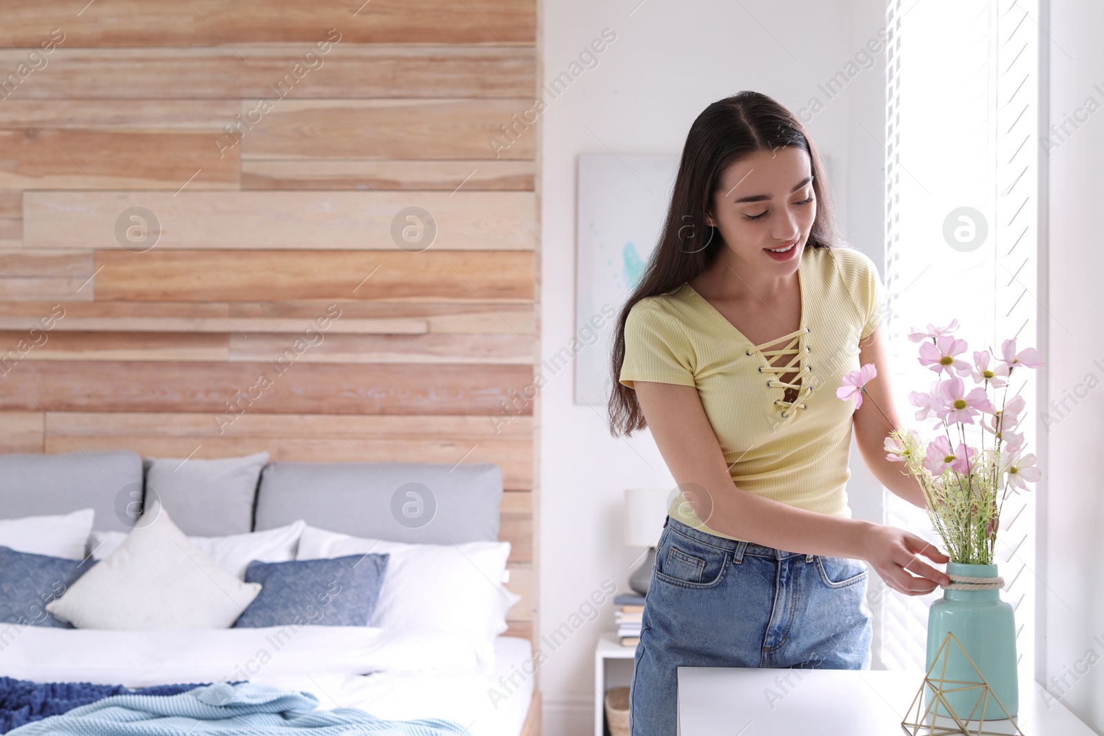 Photo of Happy woman with flowers in bedroom. Elegant interior