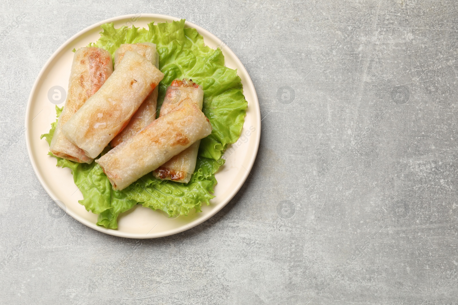 Photo of Delicious fried spring rolls on grey table, top view. Space for text