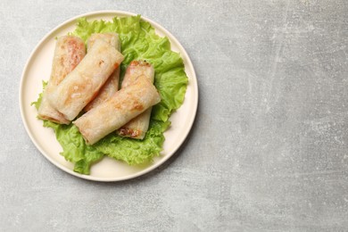 Delicious fried spring rolls on grey table, top view. Space for text