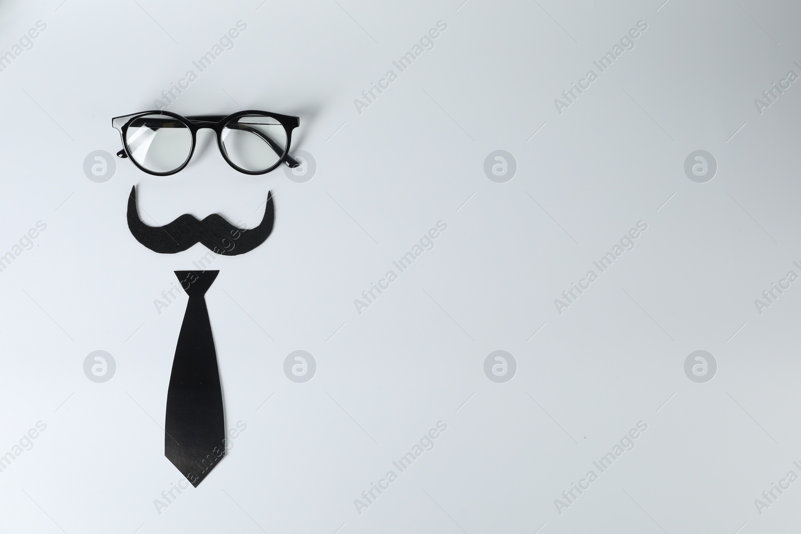 Photo of Fake mustache, tie and glasses on light background, top view. Space for text