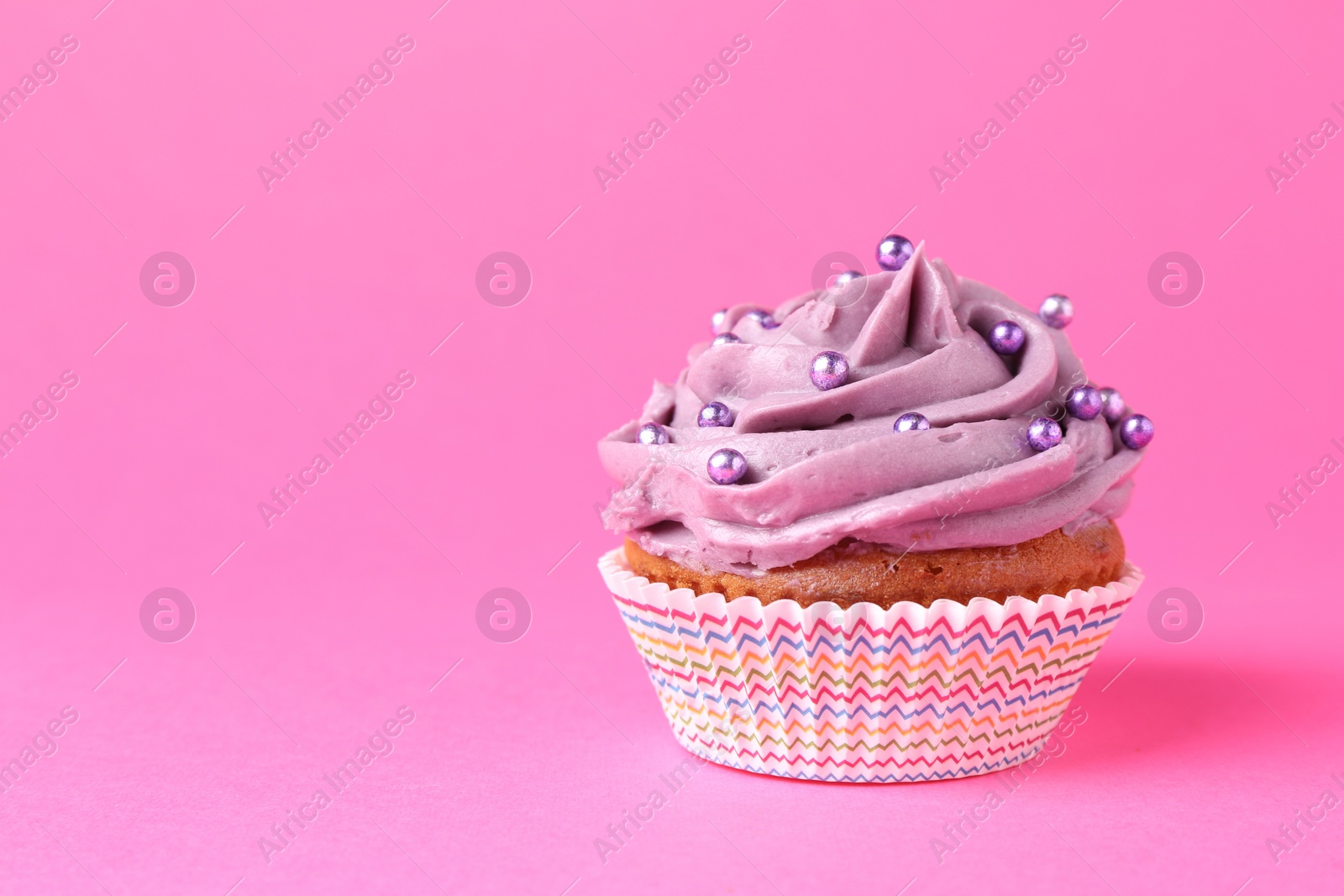 Photo of Delicious cupcake with bright cream and sprinkles on pink background. Space for text