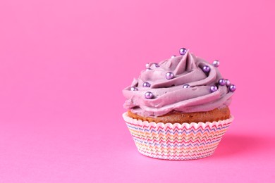 Photo of Delicious cupcake with bright cream and sprinkles on pink background. Space for text