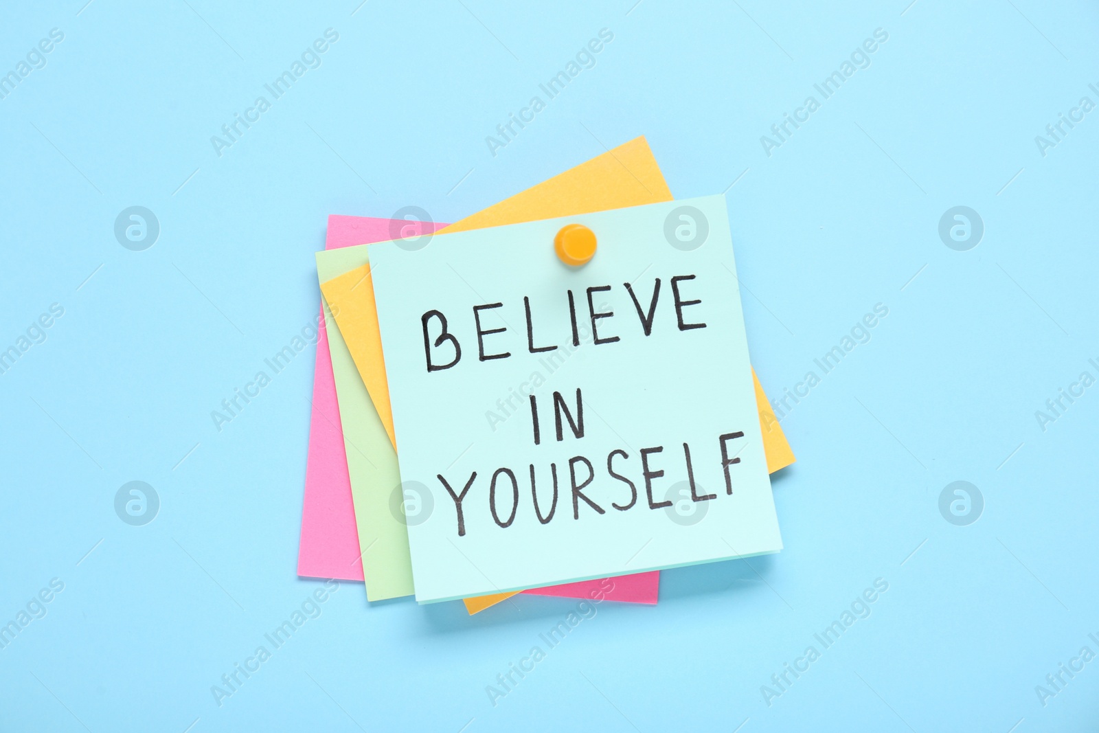 Photo of Notes with phrase Believe In Yourself on light blue background, top view. Motivational quote