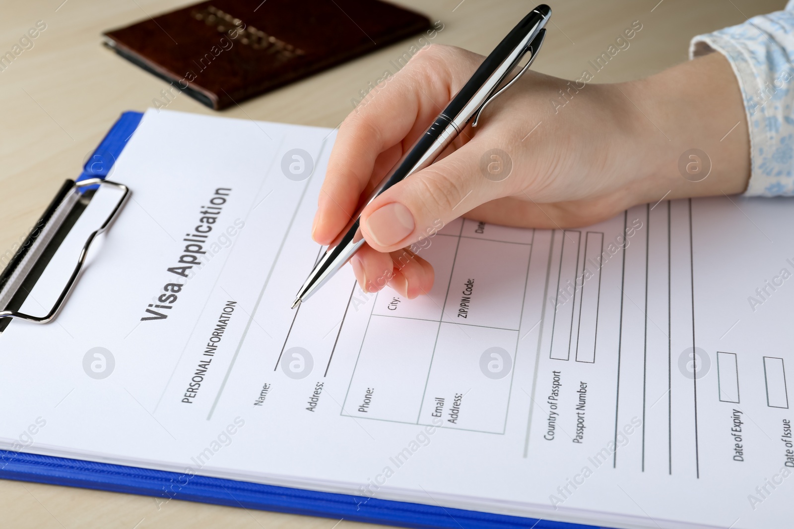 Photo of Woman filling visa application form for immigration at table, closeup