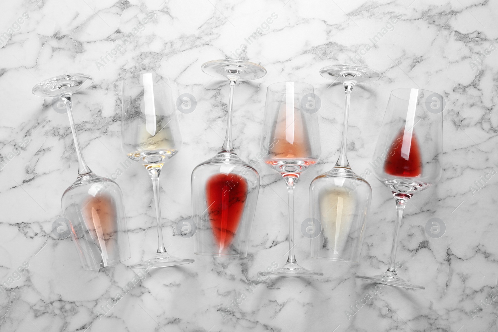 Photo of Glasses with different wine on marble background, flat lay