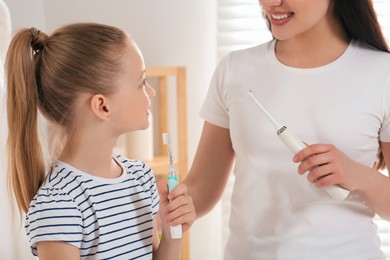 Mother and her daughter brushing teeth together in bathroom