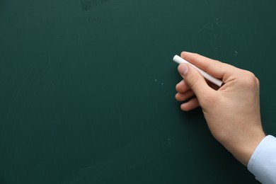 Teacher writing with chalk on green chalkboard, closeup. Space for text