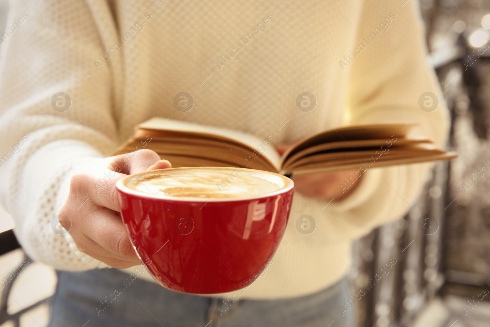 Photo of Woman with cup of coffee reading book outdoors, closeup