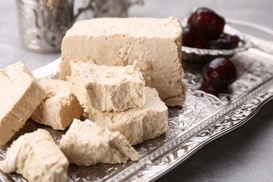 Pieces of tasty halva served on light grey table, closeup