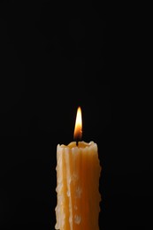Photo of Burning church wax candle on black background