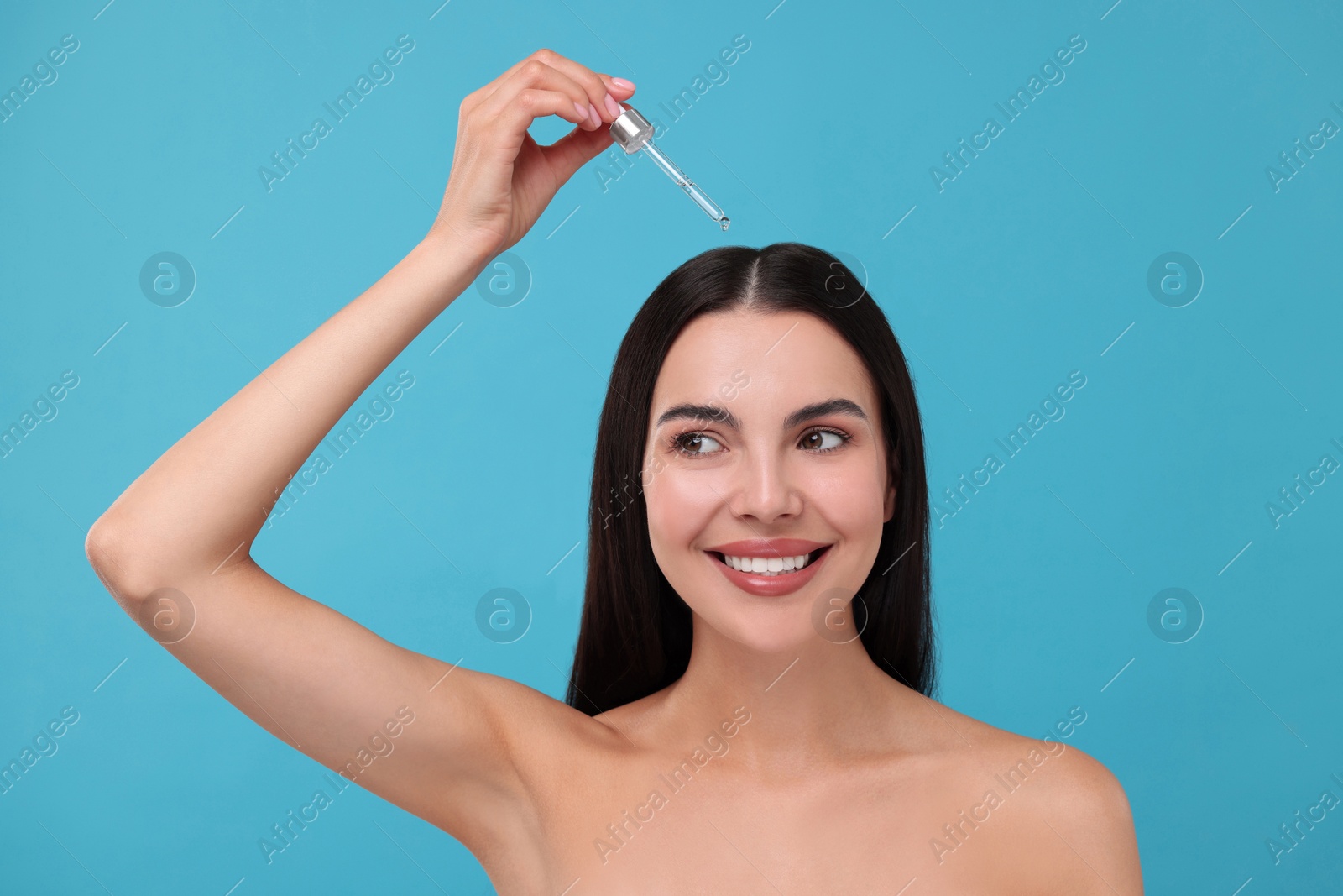 Photo of Beautiful woman applying hair serum on light blue background. Cosmetic product