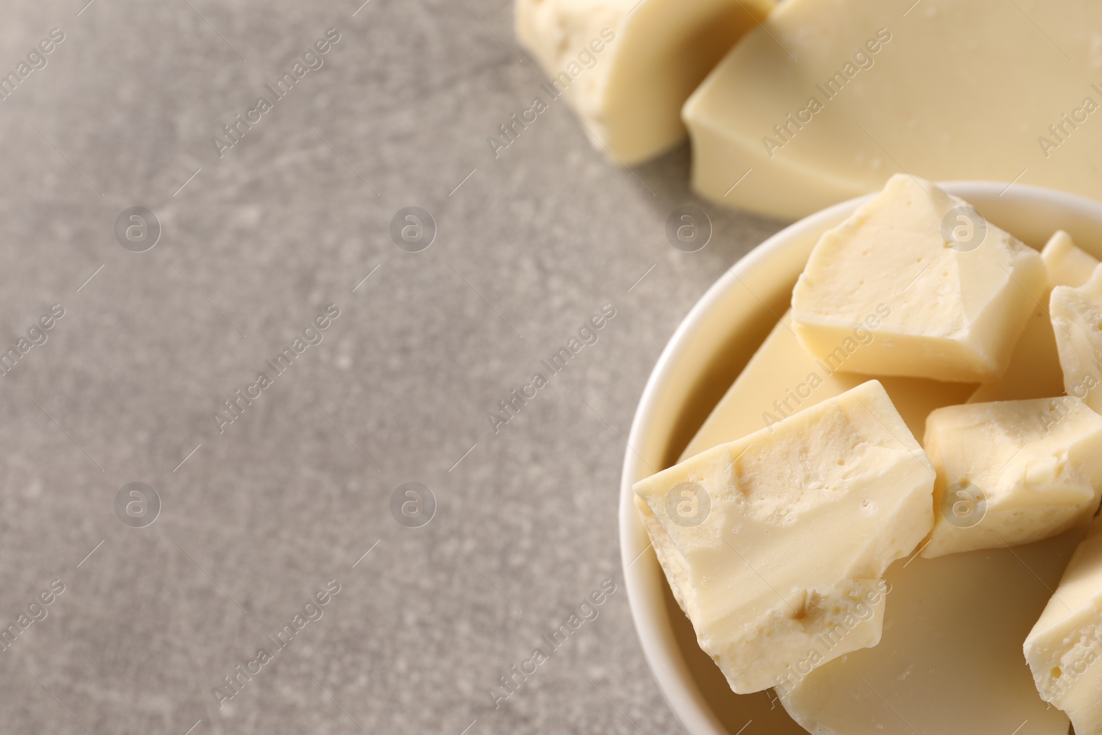 Photo of Pieces of tasty white chocolate on grey table, top view. Space for text