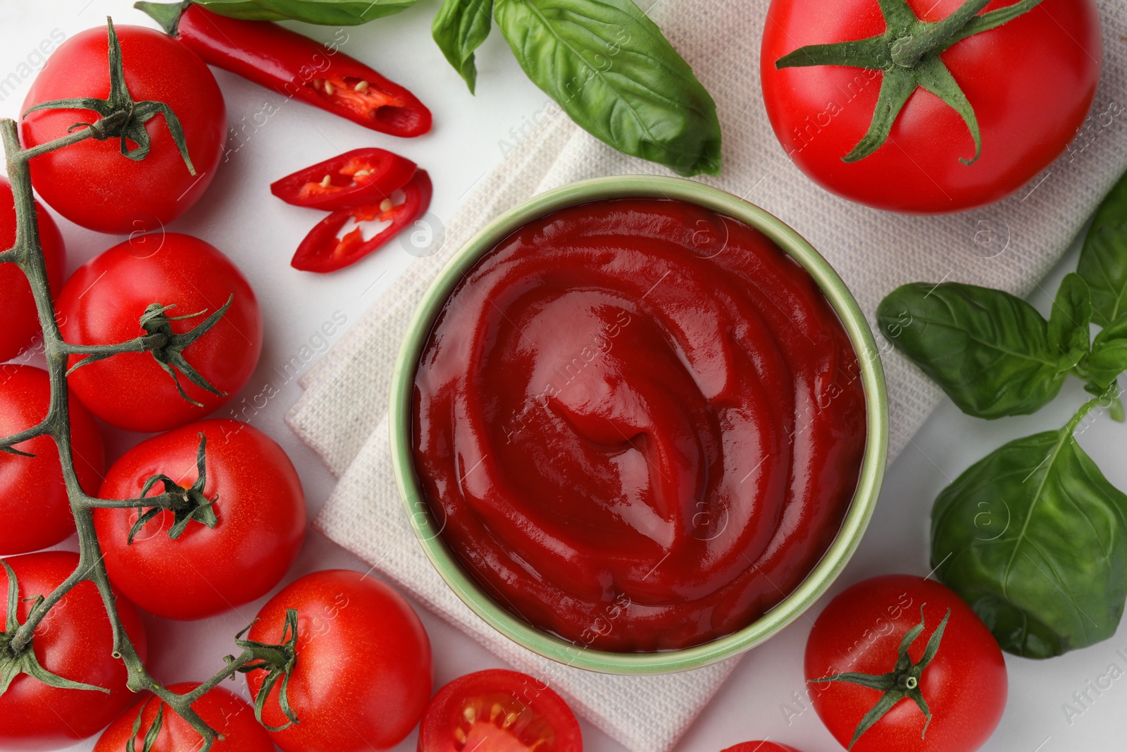 Bowl of tasty ketchup and ingredients on white table, flat lay Photo of Bowl of tasty ketchup and ingredients on white table, flat lay