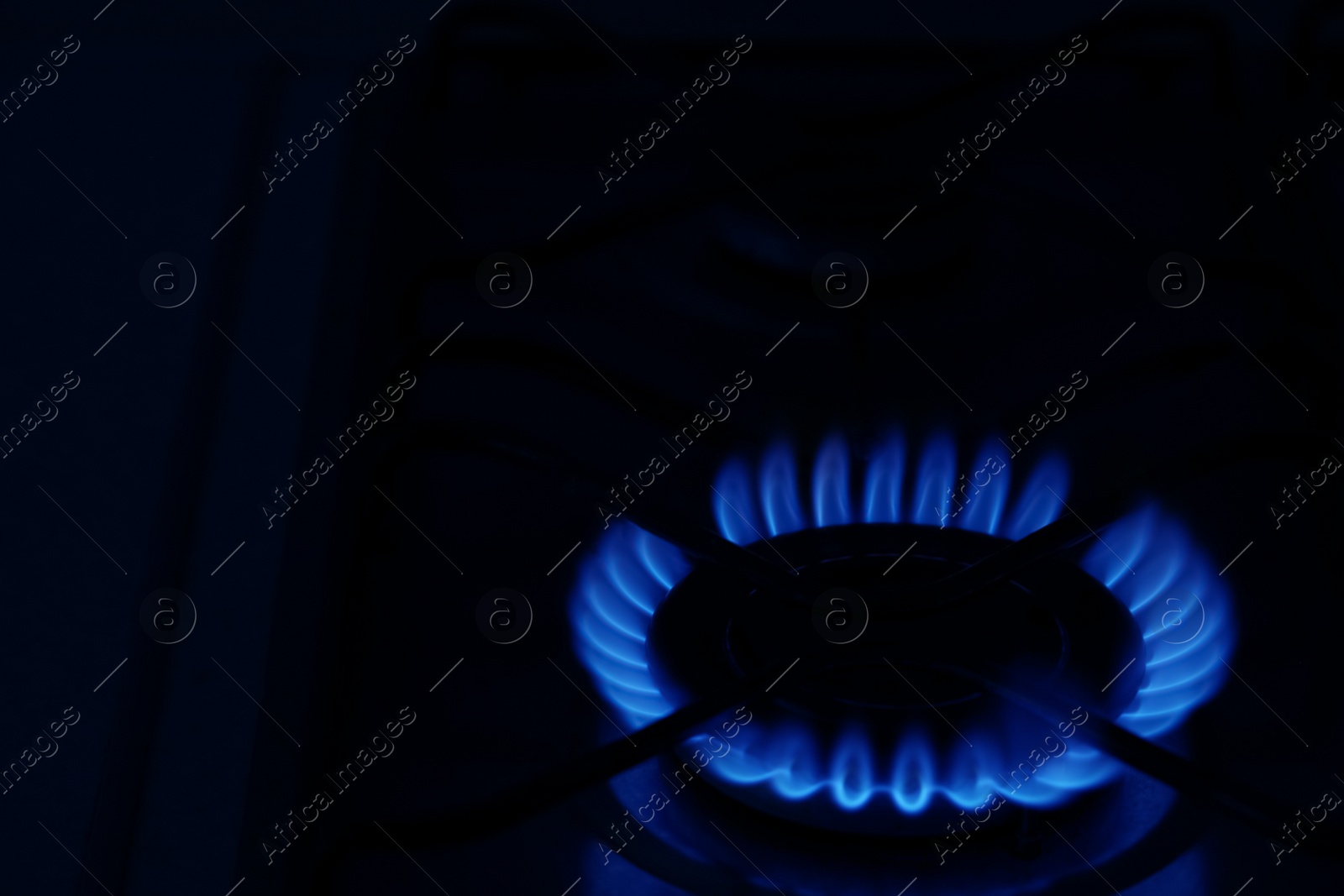 Photo of Gas burner with burning flame in darkness. Space for text