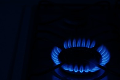 Photo of Gas burner with burning flame in darkness. Space for text