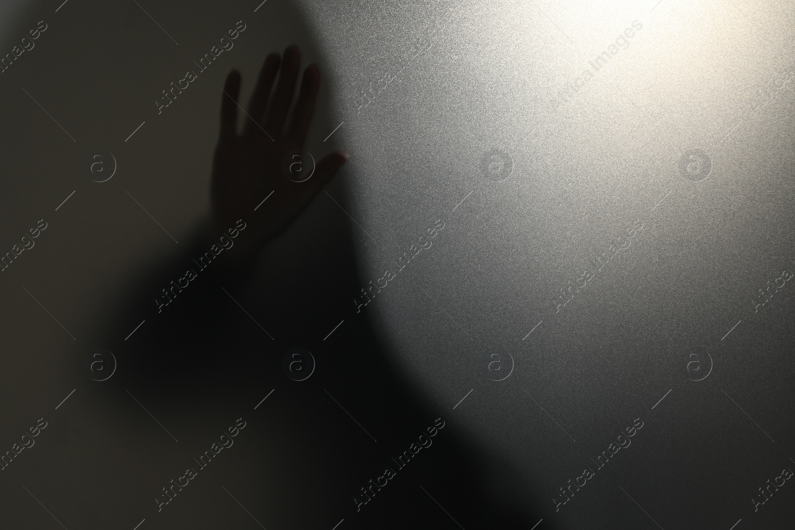 Photo of Silhouette of ghost behind glass against light grey background, closeup. Space for text