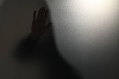 Photo of Silhouette of ghost behind glass against light grey background, closeup. Space for text