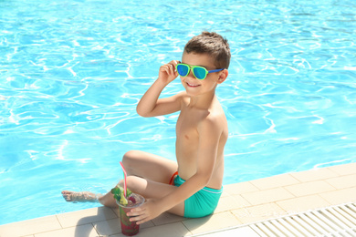 Photo of Boy with delicious refreshing drink near swimming pool