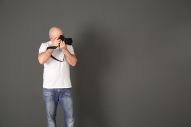 Photo of Male photographer with camera on gray background