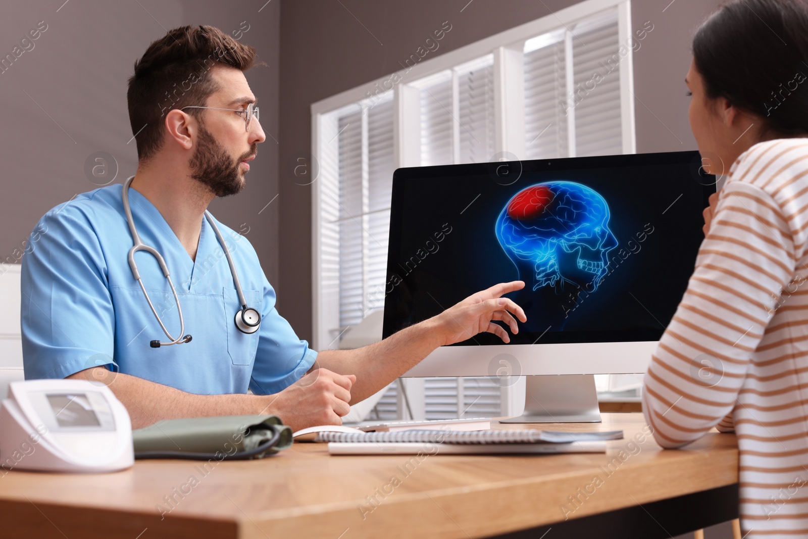 Photo of Neurologist showing brain scan to young woman in clinic