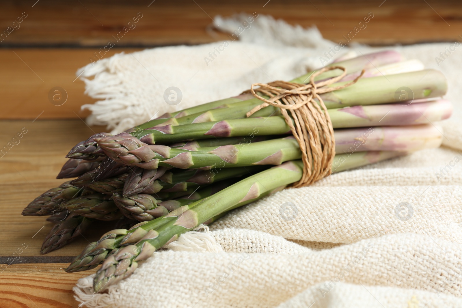 Photo of Fresh raw asparagus on wooden table, closeup