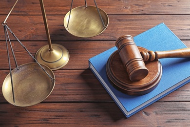 Photo of Judge's gavel, book and scales on table. Law concept