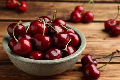 Photo of Bowl with ripe sweet cherries on wooden table, closeup