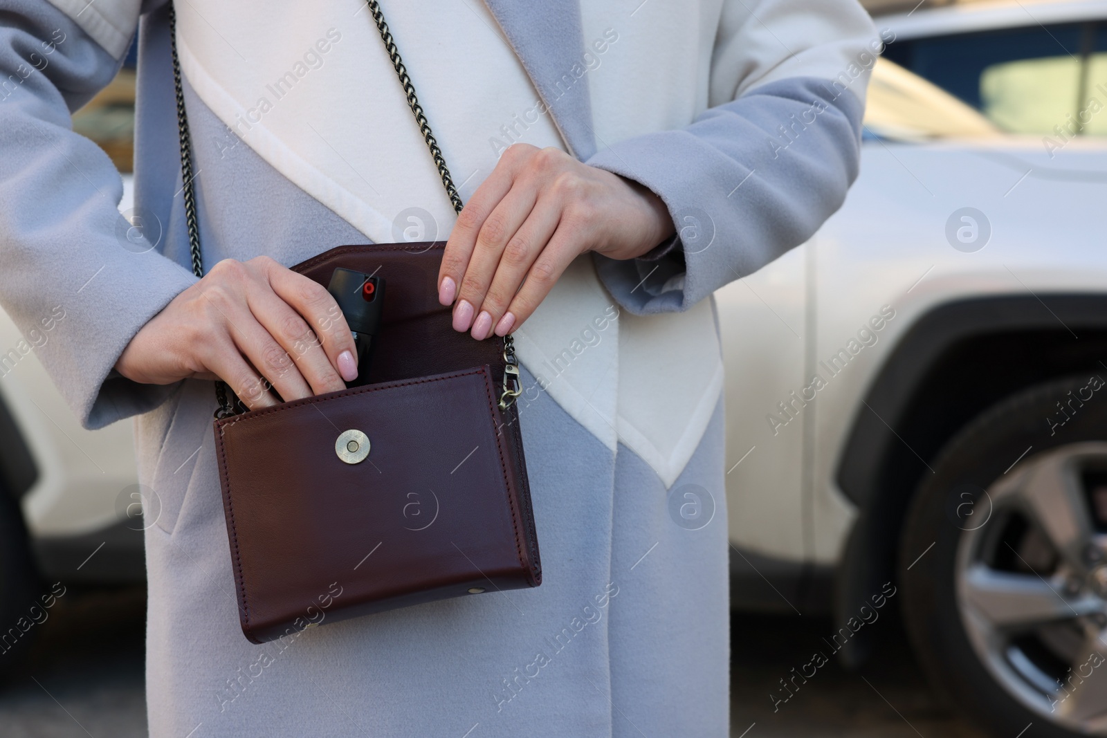 Photo of Young woman putting pepper spray into bag outdoors, closeup. Space for text