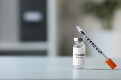 Photo of Monkeypox vaccine in vial and syringe on white table, space for text