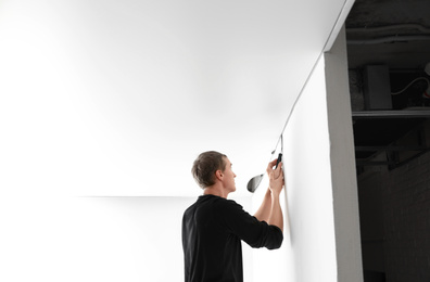 Photo of Repairman installing white stretch ceiling in room