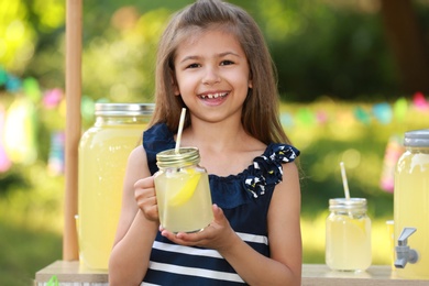 Photo of Cute little girl with natural lemonade in park. Summer refreshing drink