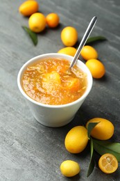 Photo of Delicious kumquat jam in bowl and fresh fruits on grey table