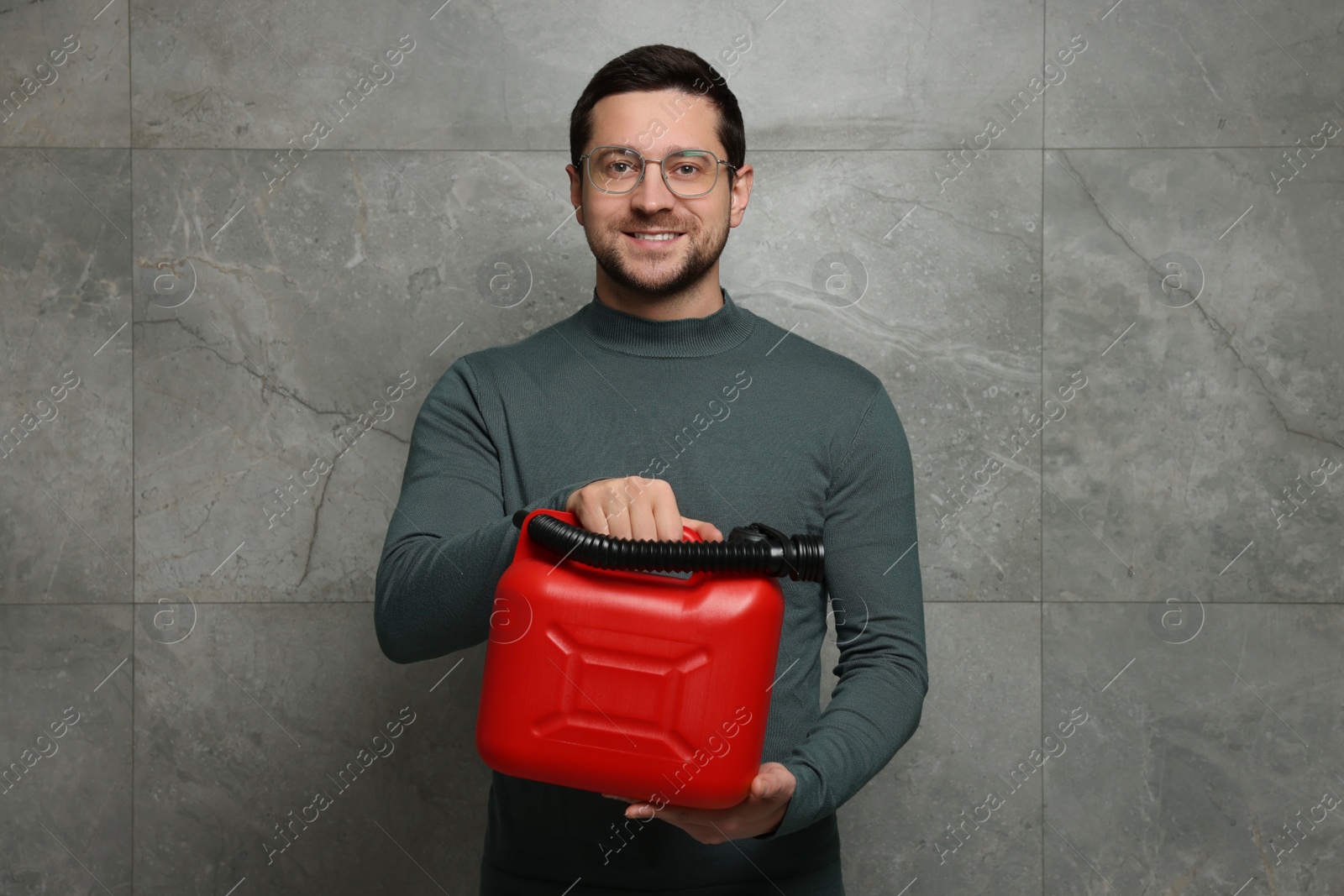 Photo of Handsome man holding red canister near grey wall