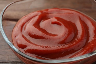 Bowl of tasty ketchup on wooden table, closeup