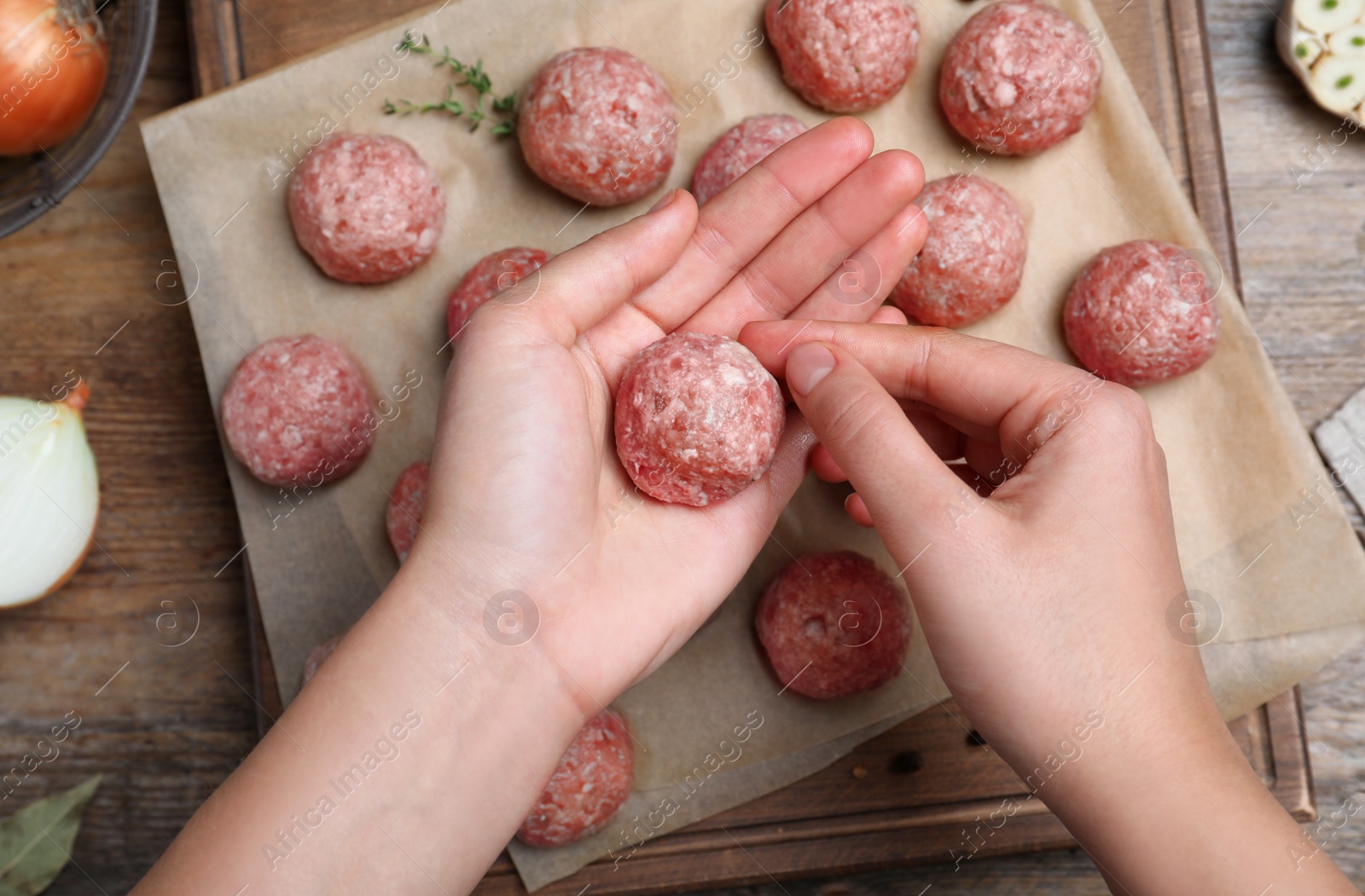 Photo of Woman making fresh raw meatballs at wooden table, top view