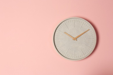 Photo of Stylish analog clock hanging on color wall. Space for text